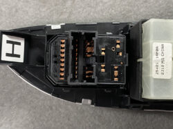 Close-up of a multi-pin automotive electrical connector with copper contacts on a black housing attached to a module.