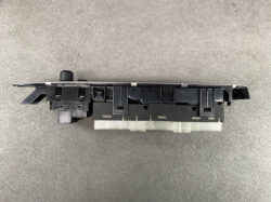 Black plastic automotive control module with a rotary knob and multiple connector housings for dash mounting.