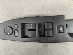 Interior car door panel with power window switches, auto button, and mirror adjustment dial (driver’s side).