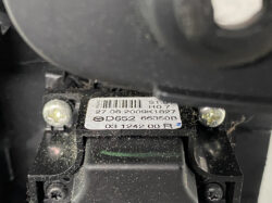 Close-up of a device label with a barcode and serial numbers on a dusty black mounting area, two screws nearby.