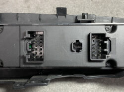 Close-up of a car stereo back panel with two multi-pin connectors and a central square port for harness connections.