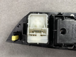 Close-up of a white, multi-pin electrical connector mounted in a black plastic housing with a small yellow actuator on the left.