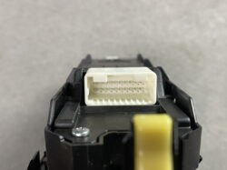 Close-up of a white rectangular electrical connector with two rows of metal pins, mounted on a black module.