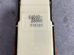 Close-up of a Toyota automotive module with stamped part numbers 84040-28060 and 515103 on a cream housing (likely interior switch/connector).