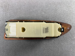 Beige Toyota automotive switch/module mounted on a wooden base with a white connector on the left and a small screw on the right; plastic part is engraved with TOYOTA.