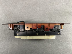 Automotive window/door control switch module with brown plastic housing, black base, and multiple connectors viewed from the side.