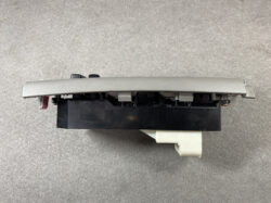 Replacement car interior switch/console module with a gray textured bezel and a white electrical connector, shown from the side