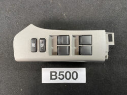 Car interior: power window switch panel with four window controls and a window lock switch, light gray plastic.