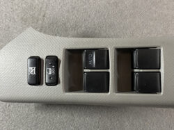 Car door control panel with window switches: two vertical locks on the left and four power window buttons on the right, one labeled AUTO on the top-left switch.