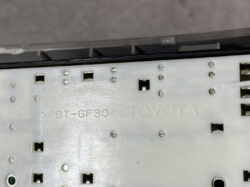 Close-up of a Toyota metal panel labeled PBT-GF30, with small square openings and screw holes (car electronics component).