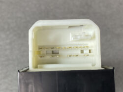 Close-up of a white electrical connector housing with gold pins inside, likely a car wiring harness plug.