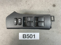 Black textured car door control panel with four power window switches and a window lock button.