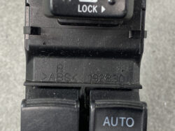 Close-up of a black vehicle control panel showing a LOCK label and an AUTO button on a switch, with ABS markings on the housing.