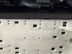 Close-up of a white Toyota dashboard fascia panel with mounting holes and connector slots.