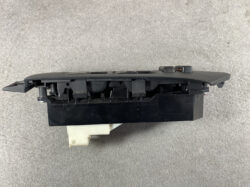 Side view of a black car window control switch module with a white electrical connector at the bottom.