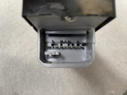Close-up of a gray automotive multi-pin electrical connector with two rows of exposed metal pins in an open housing (16 pins).