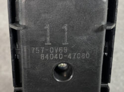 Close-up of a black plastic component with the embossed number 11 and the serial code 157-0V69 84040-47080, plus a circular recess below.