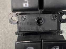 Close-up of an automotive ABS module housing with 'RH', 'ABS' and serial markings, showing mounting holes and a central cylindrical opening.