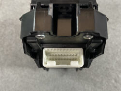 Plastic electrical connector with 24 metal pins, white receptacle inside a black housing (front view).