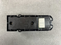 Black automotive actuator module in plastic housing with mounting posts and a white connector at one end.