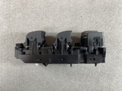 Automotive power window switch module with two rocker controls and a small orange indicator on the right.