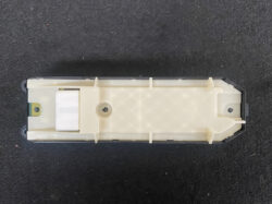 Beige rectangular electrical module with a white actuator lever on the left, mounted in a housing against a dark background.