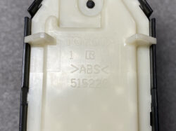 Back of a Toyota ABS module housing with embossed branding and part number 515220 (white plastic).