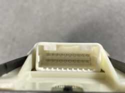 Close-up of a white rectangular automotive multi-pin connector with two rows of small metal pins inside a housing.