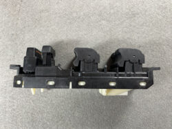 Automotive power window switch block with three window controls on a black plastic mounting rail.