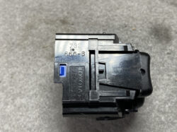 Close-up of a black automotive relay with a blue latch, showing stamped numbers (666-8, Z32) on a metal top, placed on a gray concrete surface.
