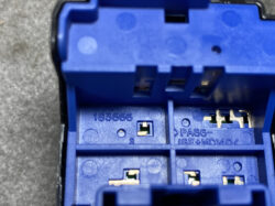 Close-up of a blue plastic electronic housing with metal contact terminals and empty slots inside.