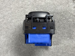 Close-up of a blue plastic electrical switch/module with a black mounting frame, viewed from above.