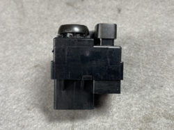Black plastic electrical relay with two top knobs on a gray background.