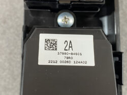 Circuit breaker with a white label showing '2A' and a QR code, plus model and serial numbers: 37990-84S01, 79R0, 2212 0026D 124A02 (close-up]. But keep concise as a product identification badge on electrical equipment.