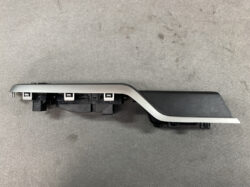 Car interior door trim piece in silver and black with multiple plastic mounting clips along the base