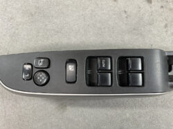 Driver-side car door control panel featuring four power window switches, a lock button, window lock, and a mirror adjustment pad with L/R buttons.