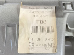 Close-up of a beige label on gray machinery showing code 'F00', a barcode, and Japanese text (Block NO B02, Unit NO).