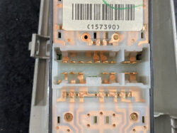 Close-up of a grey multi-pin electrical connector block with copper contact blades and a barcode sticker on top.