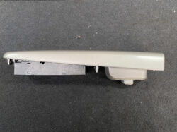 Detached gray automotive center console armrest with a storage base, shown on a dark carpeted surface