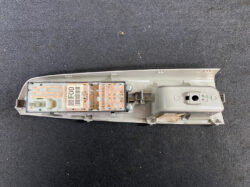 Exposed automotive interior light module with an orange printed circuit board inside a gray plastic housing on a dark surface.
