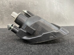 Black automotive actuator with two mounting studs and a gray electrical connector, photographed on a dark surface.