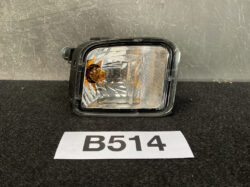 Rectangular automotive fog light with amber bulb in a black housing on a dark surface, B514 label in the foreground.