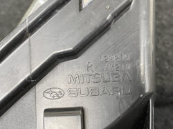 Close-up of a black plastic car part stamped with MITSUBA SUBARU and 12V21W markings.
