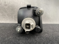 Close-up of a gray automotive actuator with a white electrical connector and mounting studs on a dark surface.