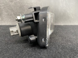 Car tail light/indicator module with clear lens, black plastic housing, and mounting hardware visible