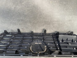 Uninstalled car dashboard center panel with circular instrument cluster housing on a scratched gray floor.