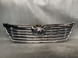 Chrome front grille of a car with a circular emblem centered among horizontal slats.