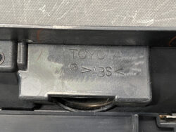 Close-up of a Toyota car part with an embossed 'TOYOTA' and 'ABS' label on a gray plastic cover.