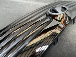 Close-up of a glossy black car hood with parallel ridges and a chrome circular air intake.