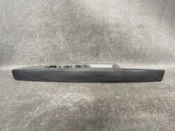 Car interior door panel featuring a long black armrest and multiple power window switches with a textured grip surface on a gray background.
